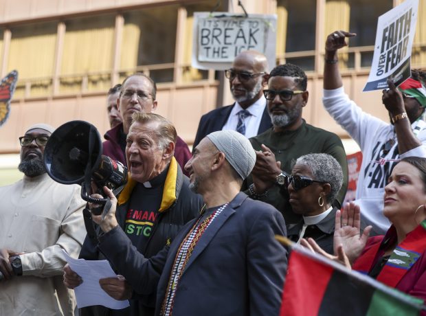 Rami Nashashibi, center, founding executive director of Inner-City Muslim Action Network, holds a bullhorn for Father Michael Pfleger as he speaks during an interfaith LIVE FREE Illinois rally in Daley Plaza on Sept. 8, 2025. (Eileen T. Meslar/Chicago Tribune)