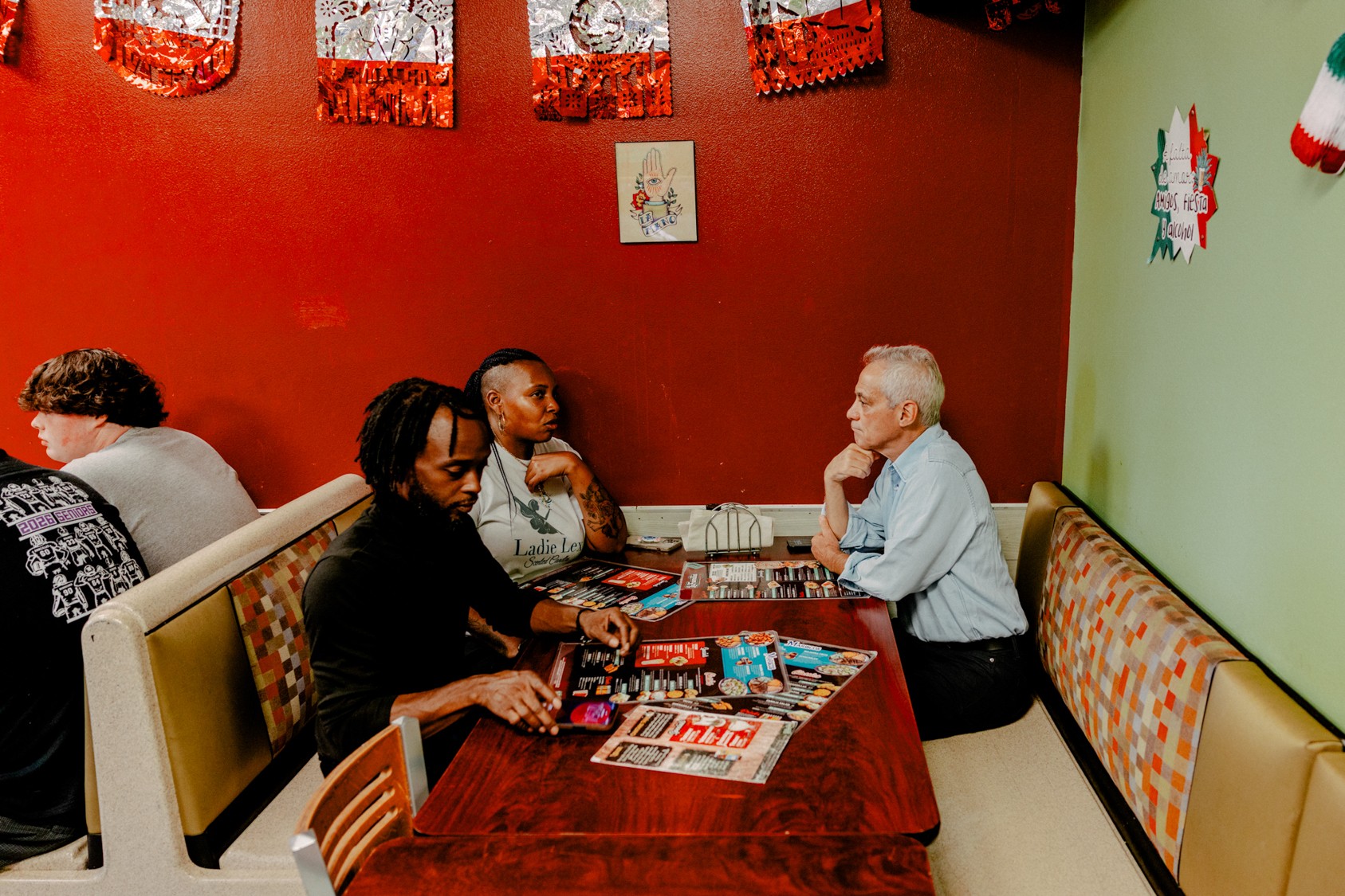 Two people sitting with Rahm Emanuel in a booth in a Mexican restaurant.