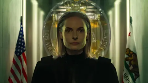 2025 Amazon Content Services LLC Rebecca Ferguson as Judge Maddox, with slicked back hair and a black outfit