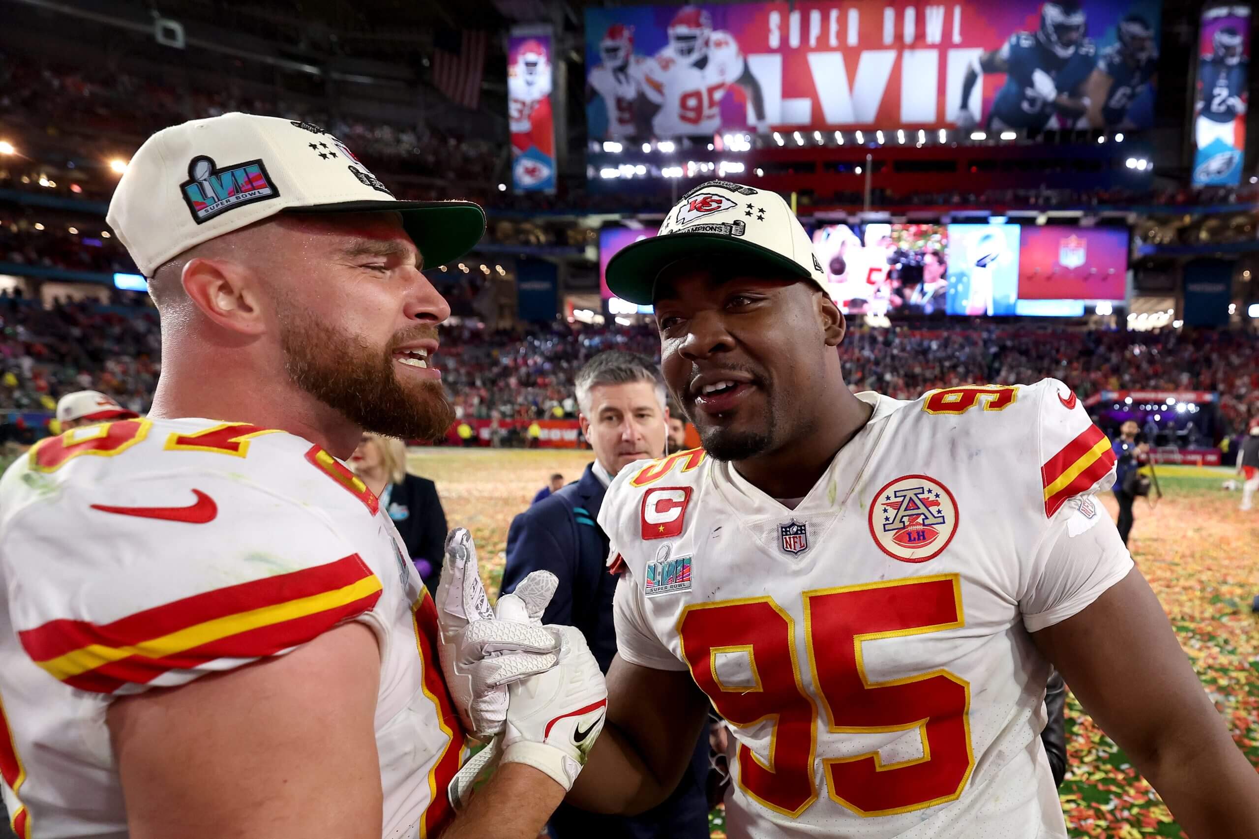 Travis Kelce (left) and Chris Jones (right) embrace in a handshake. Both players wear white uniforms.