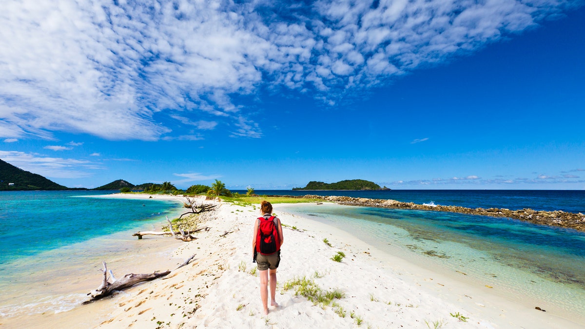 Woman with backpack just landed on sandbar in Grenada.