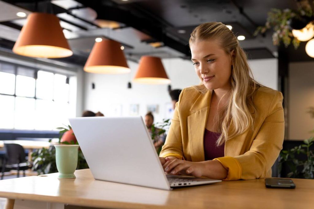 Woman using office laptop in public cafe