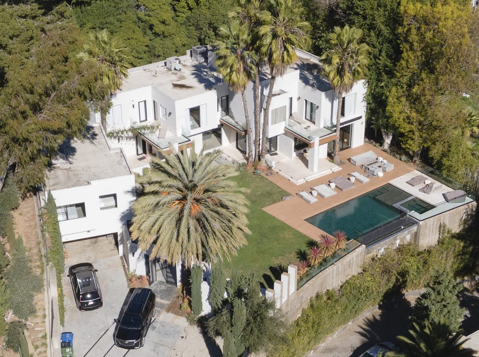 Modern two-story house with a pool and palm trees.