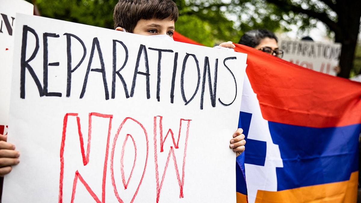 Boy holding sign in support of reparations