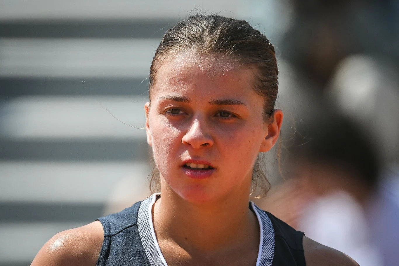 Maja Chwalińska Młoda kobieta o spiętych włosach w sportowym stroju na tle rozmazanego obszaru, prawdopodobnie po wysiłku fizycznym, z lekko spoconą twarzą i skupionym wyrazem.