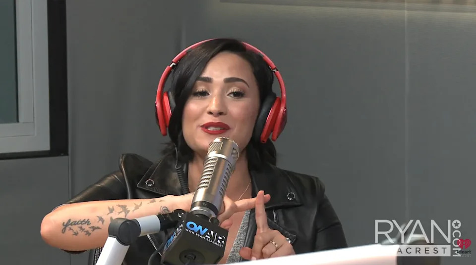 Demi speaking into a microphone in a radio studio