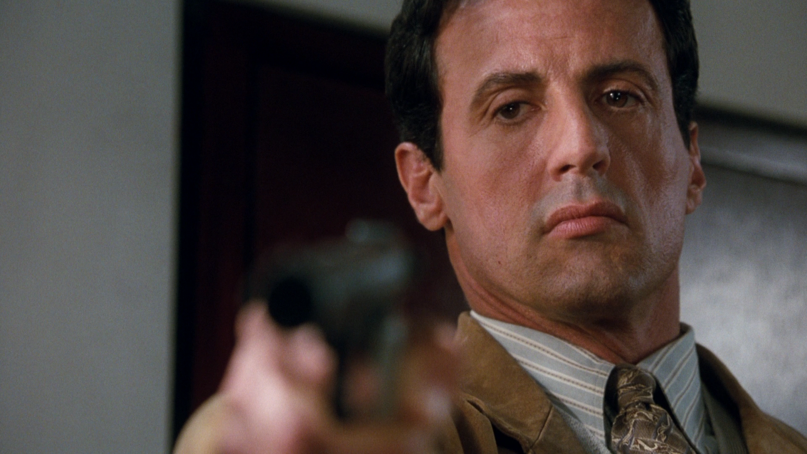 Sylvester Stallone points a silenced gun in Assassins