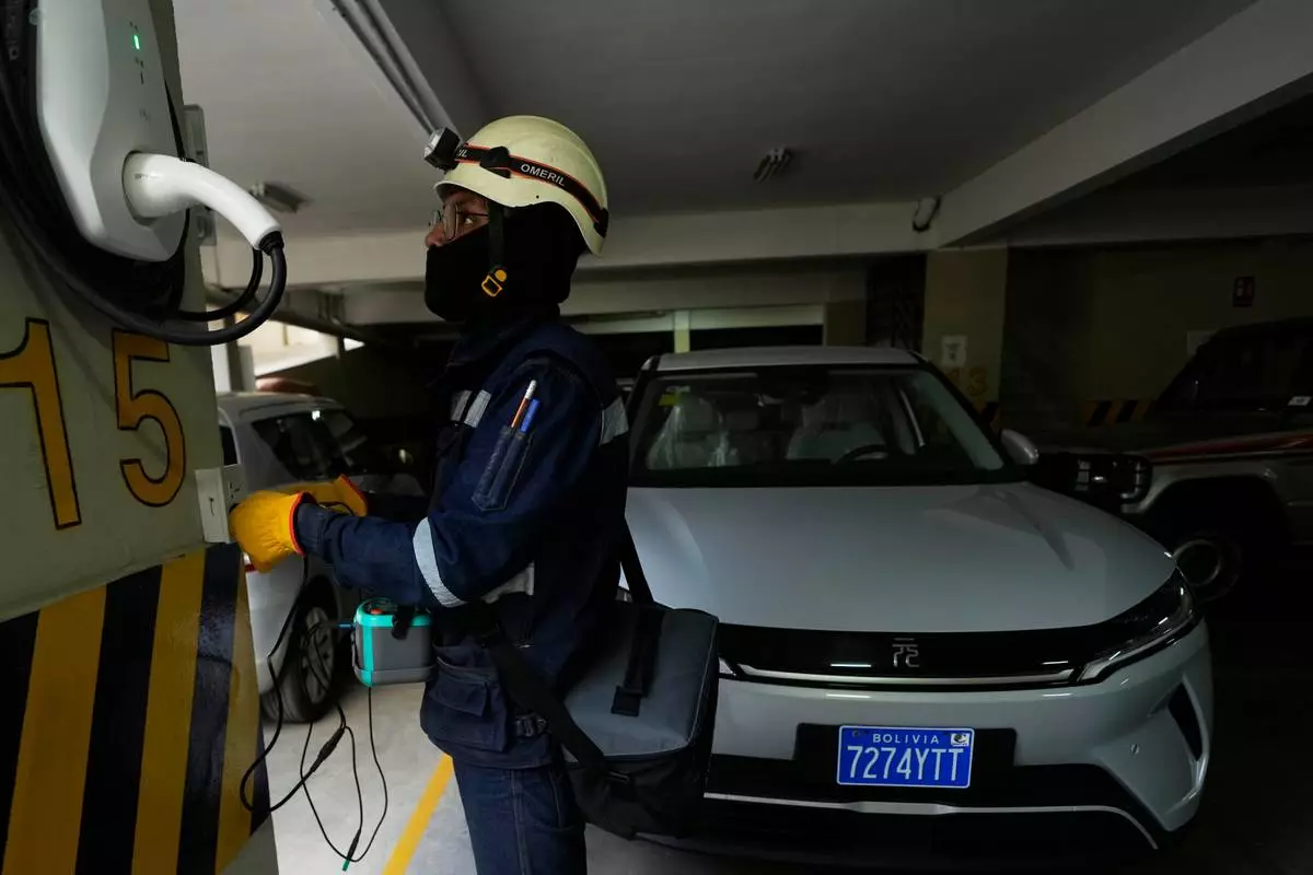 An electrician installs a home electric vehicle charging station in La Paz, Bolivia, Tuesday, April 21, 2026. (AP Photo/Juan Karita)